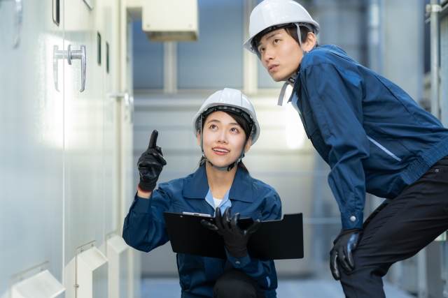 ヘルメットを着用した作業員が設備を確認しながら打ち合わせをしている様子
