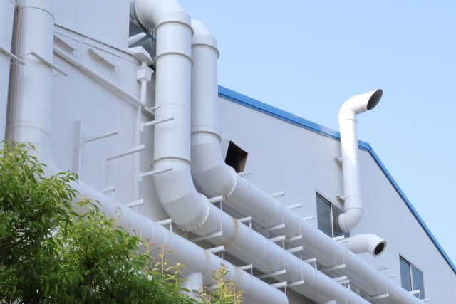 白い配管が複雑に張り巡らされた工場建物の外観